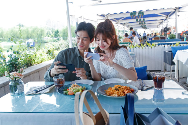 青年情侣在餐厅里用手机拍照图片下载