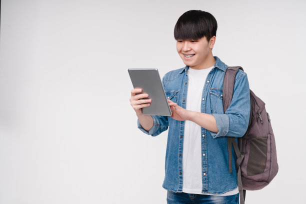 一名年轻的韩国亚裔男生正在用数码平板电脑进行在线学习，准备考试，做作业，项目，远程在线学习图片下载