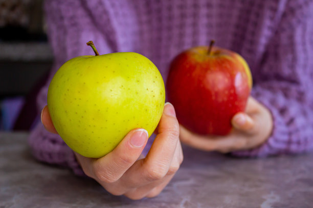 手里拿着红绿苹果的女人。图片下载