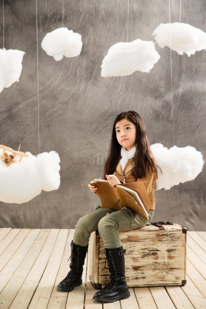 小女孩坐在行李箱上边写日记边思考图片下载
