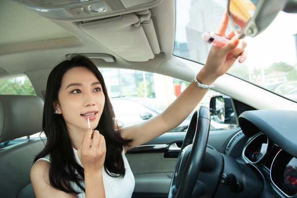 漂亮的青年女人对着后视镜化妆图片下载