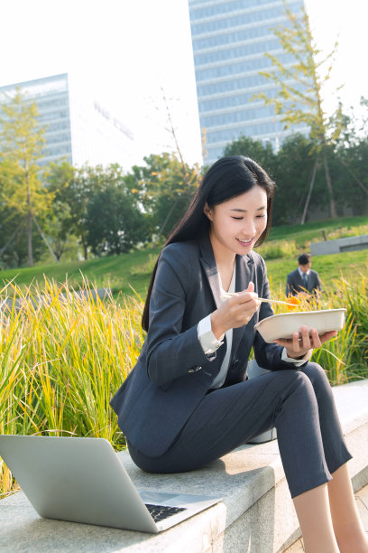 商务女性坐着户外边吃饭边工作图片下载