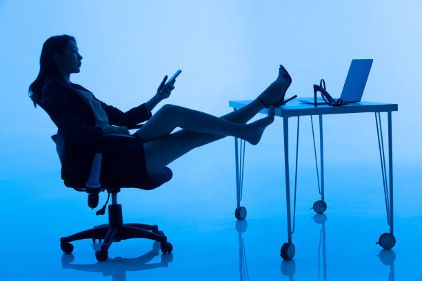 商务女士坐在办公桌前看手机图片下载