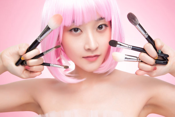 手指夹着化妆刷的年轻女孩图片下载