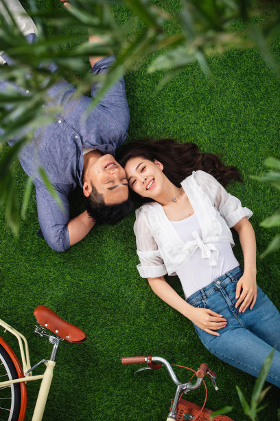 甜蜜的青年伴侣躺在草地上图片下载