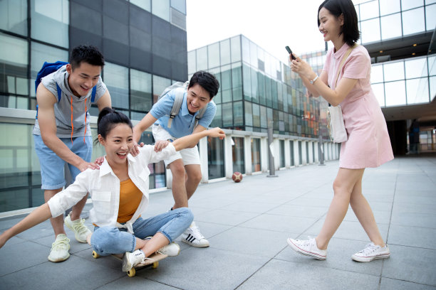 年轻男子向前推着坐在滑板上的女同学图片下载