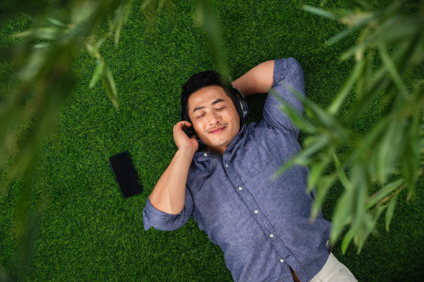 躺在草地上听音乐的青年男人图片下载