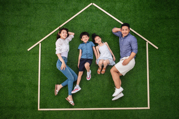 快乐的一家四口躺在草地上的房子轮廓里图片下载