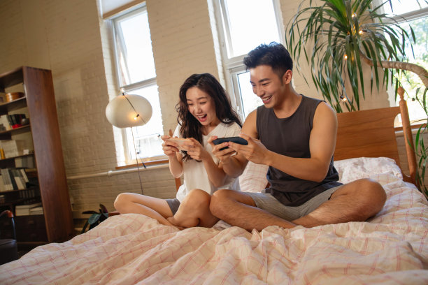 青年情侣趴在床上玩手机图片下载