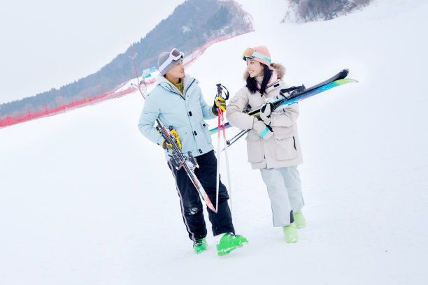 滑雪场上青年伴侣拿着雪具边走边聊图片下载
