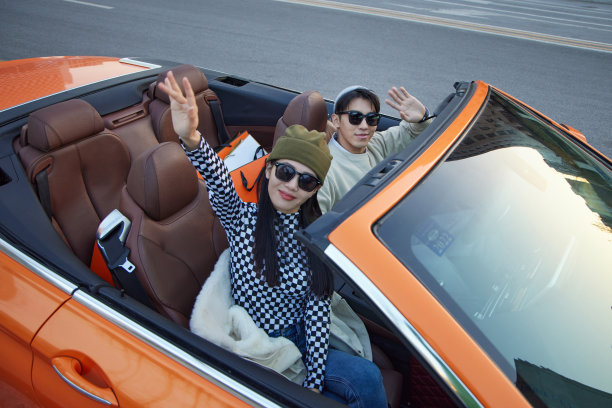 快乐的青年情侣驾驶跑车出行图片下载