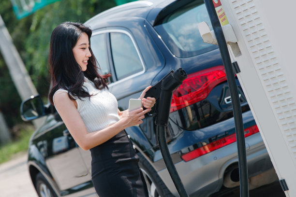 从充电桩取充电枪的漂亮青年女人图片下载
