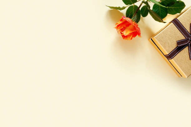 美丽的黄色玫瑰与金色的礼盒和蝴蝶结在精致的黄色纸背景。婚礼邀请卡。为你的文本留出位置。图片下载