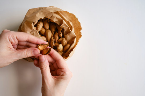 用牛皮纸袋装杏仁，背景色淡。健康食品。健康的素食自然小吃。有机食品。坚果特写图片下载