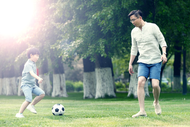 快乐父子在草地上踢足球图片下载