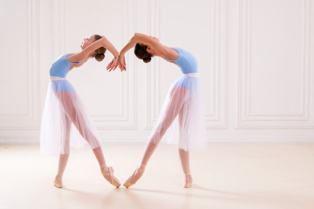 年轻的芭蕾舞演员在舞蹈室排练。一排快乐的年轻芭蕾舞演员在练芭蕾杠，专注于第一个女孩。图片下载