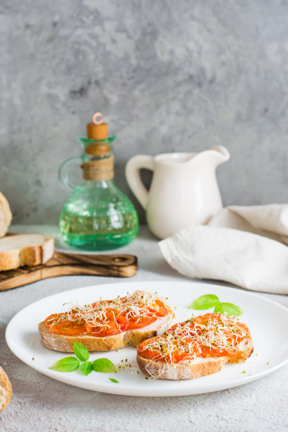 开胃的三明治，晒干的西红柿，三叶草和苜蓿芽放在桌子上的盘子里。饮食有机食品。俯视图图片下载