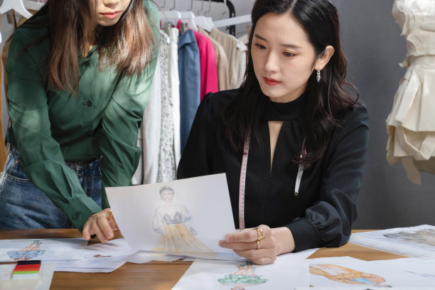 服装设计师讨论手绘设计图图片下载