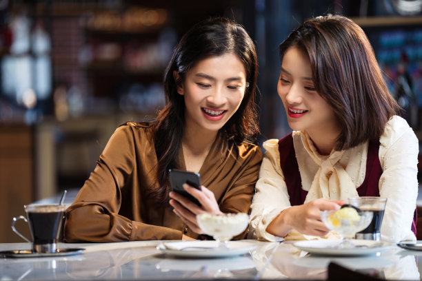年轻闺蜜在咖啡馆使用手机图片下载