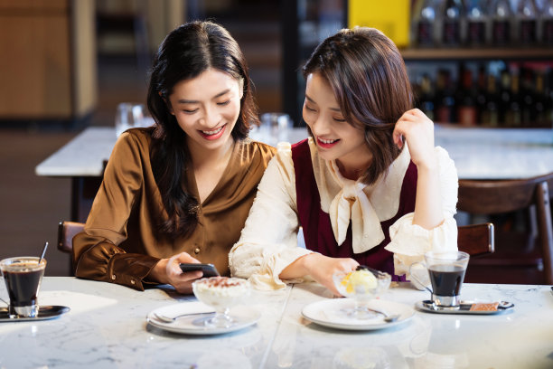 年轻闺蜜在咖啡馆使用手机图片下载