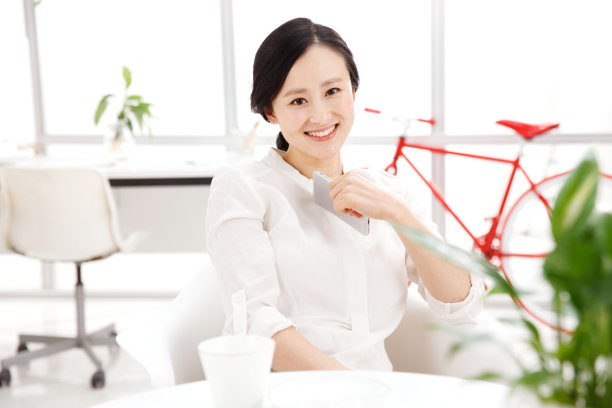 青年女人在办公室里拿着手机图片下载