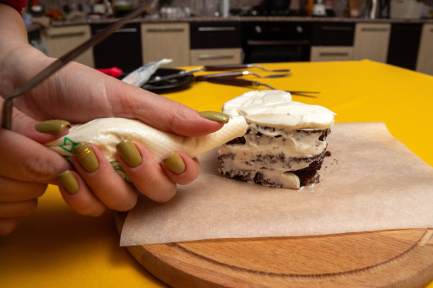 妇女的手从糕点袋上涂抹奶油在便当蛋糕饼干上。特写镜头。在家做甜点的过程。有选择性的重点。图片下载