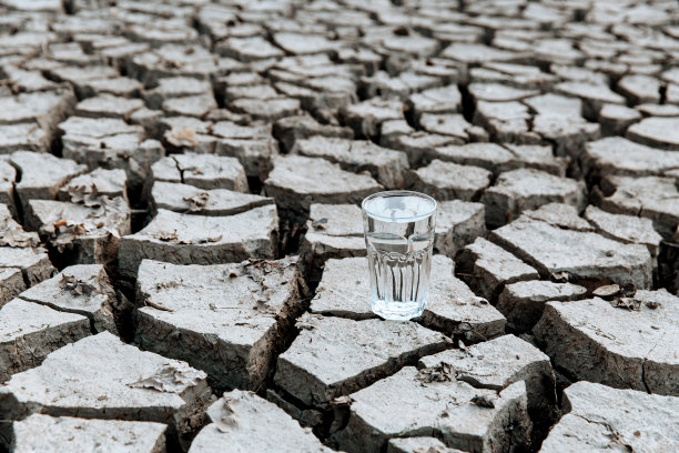 在干裂的土地上，有一杯清澈透明的水图片下载