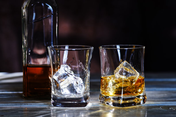 一杯琥珀色的苏格兰威士忌加冰块，背景是深色的图片下载