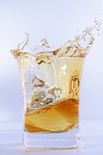 一杯加冰的老威士忌。在明亮的背景下，一杯洒着冰的威士忌图片下载