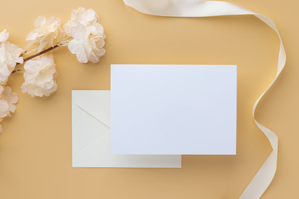 空白贺卡邀请模型5x7在信封上与粉红色的花和丝带在纸背景上，平躺，模型图片下载