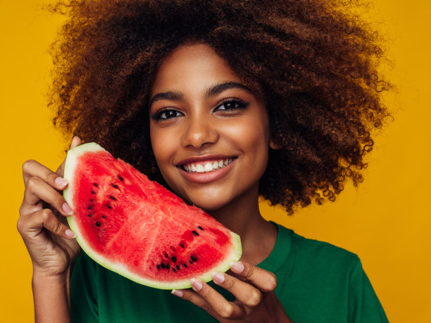 一个漂亮的非洲发型女孩和西瓜的工作室肖像图片下载