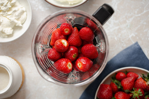 新鲜成熟的草莓放在大理石桌上的搅拌机里。前视图。图片下载