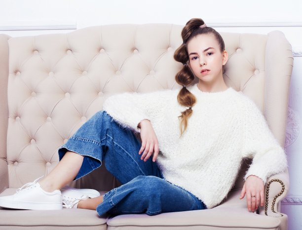 穿着休闲衣服的时尚少女坐在沙发上摆姿势图片下载