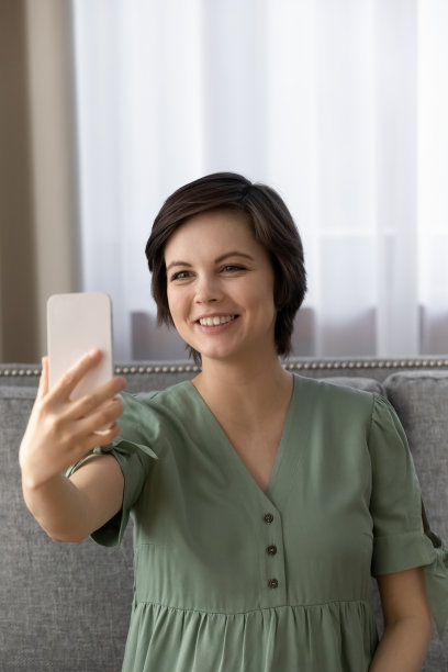 漂亮的孕妇坐在沙发上拍可爱的自拍图片下载