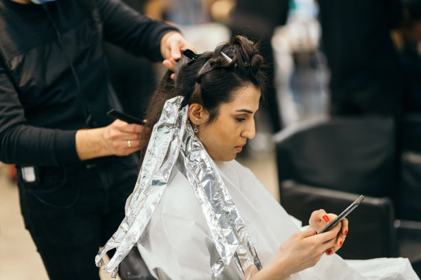 年轻女子在发廊用智能手机放松图片下载