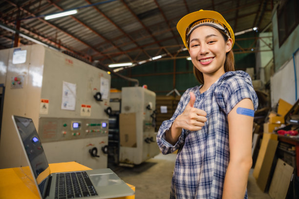 接受新冠病毒疫苗注射后，一名亚裔年轻工人指着戴着绷带的他的手臂。为工业工厂卫生保健部门的基本工人接种疫苗。图片下载