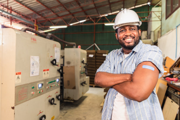 非洲工人在接种新冠病毒疫苗后指着扎着绷带的手臂。为工业工厂卫生保健部门的基本工人接种疫苗。图片下载