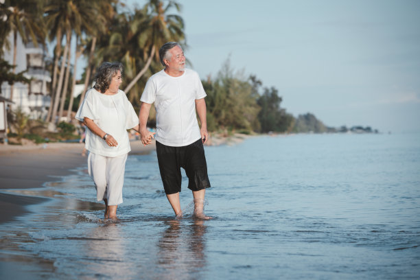 浪漫的亚洲老年夫妇手牵手漫步在夏日的沙滩夕阳下。旅游休闲和活动退休后的假期和夏季概念。假期和放松的时间。图片下载