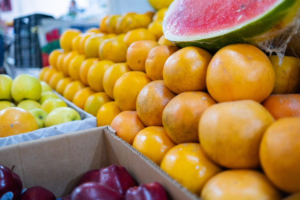 五颜六色的水果摊上有橙子、切成薄片的西瓜、苹果等图片下载