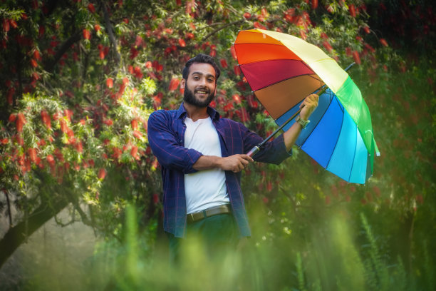 亚洲印度男孩带着伞在春天的季节与花的背景图片下载