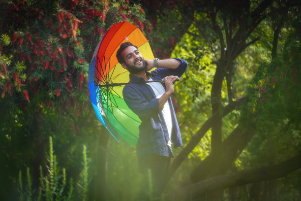 亚洲印度男孩带着伞在春天的季节与花的背景图片下载