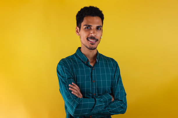 一个穿着西装的黑人在画室里被黄色的背景孤立起来。孤立的商人，充满戏剧性的光芒。图片下载