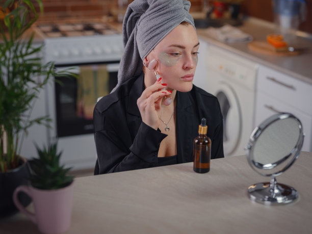 年轻女子在家用面部刮痧玉板照镜子。图片下载