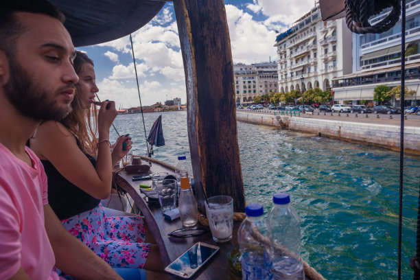 侧视图照片，一个年轻人坐在一个船酒吧，看着美丽的大海图片下载