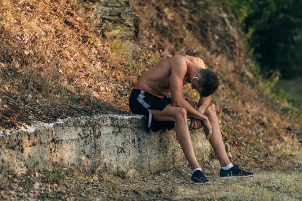 疲惫英俊的运动员在公园慢跑后站着休息图片下载