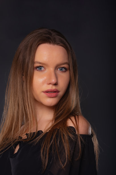 一个性感的女模特的特写肖像，看起来严肃，而摆姿势在工作室里的黑色衣服图片下载