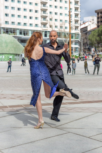 多云的一天，在西班牙首都马德里的España广场，多民族舞蹈组合正在跳探戈。路人看了图片下载