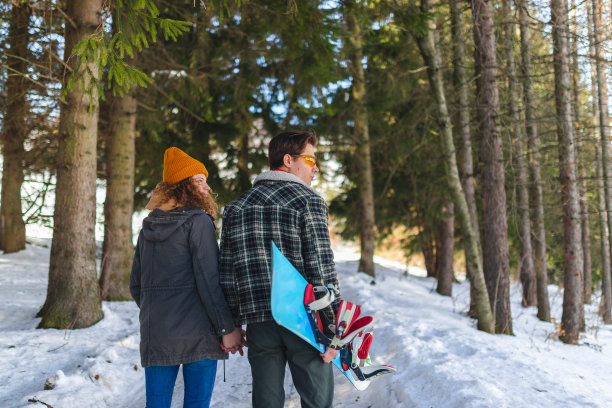 一对年轻的异性恋情侣手牵着手走过雪原森林图片下载