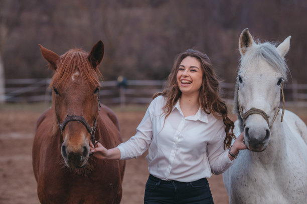 年轻女子在大自然中遛两匹马。图片下载