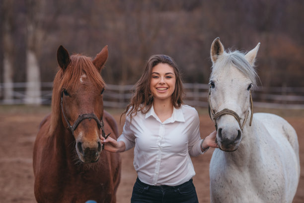 年轻女子在大自然中遛两匹马。图片下载